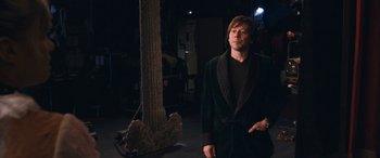 Movie still from “Venus in Fur” (2013), directed by Roman Polanski – A man standing in front of a tree in a dark room; Medium shot, Over the shoulder angle