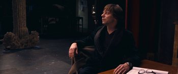 Movie still from “Venus in Fur” (2013), directed by Roman Polanski – A man sitting on top of a wooden bench; Medium shot, High angle