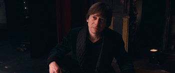Movie still from “Venus in Fur” (2013), directed by Roman Polanski – A man sitting in a dark room wearing a black jacket; Medium shot, Over the shoulder angle