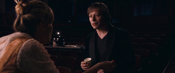 Movie still from “Venus in Fur” (2013), directed by Roman Polanski – A man is holding a cup in his hand; Medium shot, Over the shoulder angle