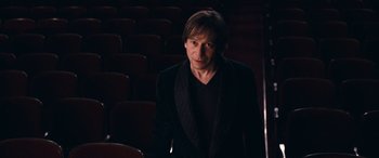Movie still from “Venus in Fur” (2013), directed by Roman Polanski – A man standing in front of a row of seats; Medium shot, High angle
