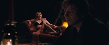 Movie still from “Venus in Fur” (2013), directed by Roman Polanski – A woman sitting on top of a red couch next to a man; Medium shot, Over the shoulder angle
