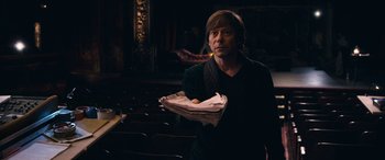 Movie still from “Venus in Fur” (2013), directed by Roman Polanski – A man holding a tray of food while standing in a room; Medium shot, High angle