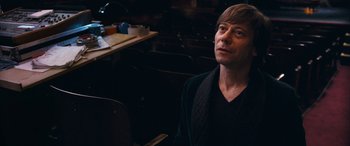 Movie still from “Venus in Fur” (2013), directed by Roman Polanski – A man sitting in front of a row of chairs; Close Up shot, High angle