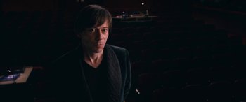 Movie still from “Venus in Fur” (2013), directed by Roman Polanski – A man standing in front of an audience in a dark room; Medium shot, High angle