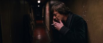 Movie still from “Venus in Fur” (2013), directed by Roman Polanski – A man smoking a cigarette in an alley way; Medium shot, Low angle