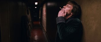 Movie still from “Venus in Fur” (2013), directed by Roman Polanski – A man is smoking a cigarette in a dark hallway; Medium shot, Low angle
