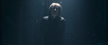 Movie still from “Venus in Fur” (2013), directed by Roman Polanski – A man in a black shirt is standing in a dark room; Medium shot, Low angle