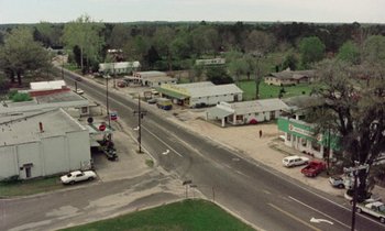 Movie still from “Vernon, Florida” (1981), directed by Errol Morris – An aerial view of an empty street with cars parked on the side of the road; Extreme Wide shot, High angle