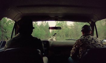 Movie still from “Vernon, Florida” (1981), directed by Errol Morris – Two people in the back seat of a car looking out the window; Wide shot, High angle
