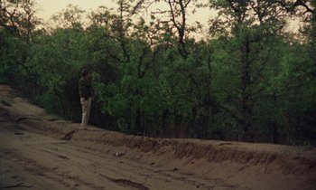 Movie still from “Vernon, Florida” (1981), directed by Errol Morris – A man standing on top of a dirt hill; Extreme Wide shot, Low angle
