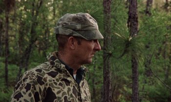 Movie still from “Vernon, Florida” (1981), directed by Errol Morris – A man wearing a camouflage jacket and a hat; Medium shot, Over the shoulder angle