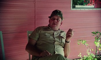 Movie still from “Vernon, Florida” (1981), directed by Errol Morris – A man sitting on a chair smoking a cigarette; Close Up shot, Low angle