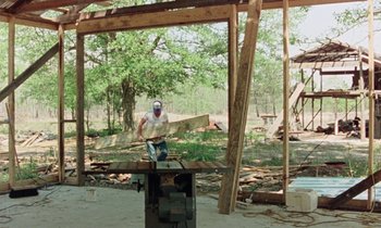 Movie still from “Vernon, Florida” (1981), directed by Errol Morris – A man is working on a wooden table; Wide shot, Low angle
