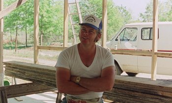 Movie still from “Vernon, Florida” (1981), directed by Errol Morris – A man wearing a white shirt and a blue hat; Medium shot, Over the shoulder angle