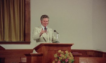 Movie still from “Vernon, Florida” (1981), directed by Errol Morris – A man standing at a podium giving a speech; Medium shot, High angle