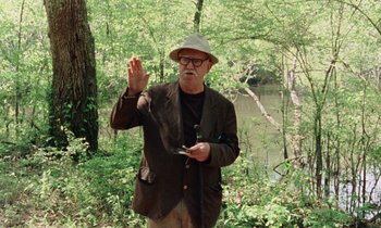 Movie still from “Vernon, Florida” (1981), directed by Errol Morris – An older man holding a cell phone in his hand; Medium shot, Over the shoulder angle