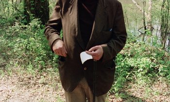 Movie still from “Vernon, Florida” (1981), directed by Errol Morris – A man in a brown jacket holding a book in his hands; Medium shot, High angle