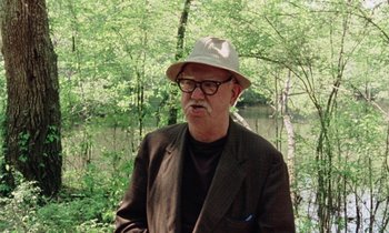 Movie still from “Vernon, Florida” (1981), directed by Errol Morris – An older man wearing a hat standing in a wooded area; Close Up shot, Over the shoulder angle