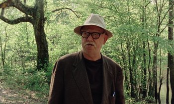 Movie still from “Vernon, Florida” (1981), directed by Errol Morris – An older man wearing glasses and a hat in a wooded area; Close Up shot, Low angle