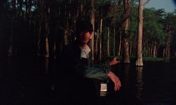 Movie still from “Vernon, Florida” (1981), directed by Errol Morris – A man sitting in a boat in the middle of a river; Medium shot, Low angle