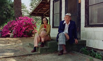 Movie still from “Vernon, Florida” (1981), directed by Errol Morris – A man and a woman sitting on the steps of a house; Wide shot, Low angle