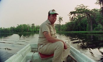 Movie still from “Vernon, Florida” (1981), directed by Errol Morris – A man sitting in a boat on a river; Medium shot, Low angle