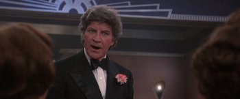 Movie still from “Victor/Victoria” (1982), directed by Blake Edwards – A man in a tuxedo with a flower in his hair; Close Up shot, Low angle