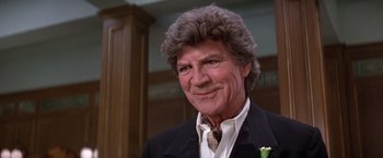 Movie still from “Victor/Victoria” (1982), directed by Blake Edwards – An older man in a suit and tie smiling for the camera; Close Up shot, Low angle