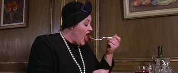 Movie still from “Victor/Victoria” (1982), directed by Blake Edwards – A woman wearing a black hat eating a piece of food; Close Up shot, Overhead angle