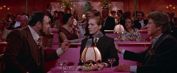 Movie still from “Victor/Victoria” (1982), directed by Blake Edwards – A man sitting at a table in front of other people; Medium shot, Over the shoulder angle