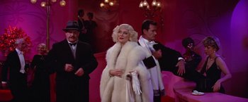Movie still from “Victor/Victoria” (1982), directed by Blake Edwards – A woman in a white fur coat standing next to a man in a black suit; Medium shot, Over the shoulder angle
