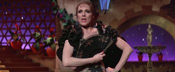 Movie still from “Victor/Victoria” (1982), directed by Blake Edwards – A woman holding a fan while wearing a dress; Medium shot, Over the shoulder angle