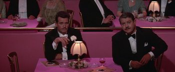 Movie still from “Victor/Victoria” (1982), directed by Blake Edwards – A man sitting at a dinner table with two other men; Medium shot, High angle