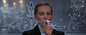 Movie still from “Victor/Victoria” (1982), directed by Blake Edwards – A woman in a suit holding a cigarette in her mouth; Close Up shot, Low angle