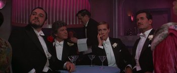 Movie still from “Victor/Victoria” (1982), directed by Blake Edwards – A man and a woman in tuxedos sitting at a table with martini glasses; Medium shot, Over the shoulder angle