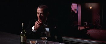 Movie still from “Victor/Victoria” (1982), directed by Blake Edwards – A man sitting at a table with a glass of wine; Medium shot, Over the shoulder angle