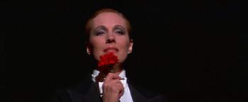 Movie still from “Victor/Victoria” (1982), directed by Blake Edwards – A woman holding a red flower in her mouth; Close Up shot, Low angle