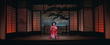 Movie still from “Victor/Victoria” (1982), directed by Blake Edwards – A woman dressed in a red and white kimono standing in front of a painting; Wide shot, High angle