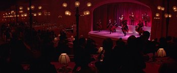 Movie still from “Victor/Victoria” (1982), directed by Blake Edwards – A group of people sitting at tables in front of a stage; Extreme Wide shot, High angle