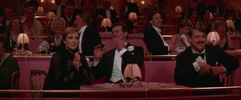 Movie still from “Victor/Victoria” (1982), directed by Blake Edwards – A group of people sitting at a table in front of a crowd of people; Medium shot, Over the shoulder angle