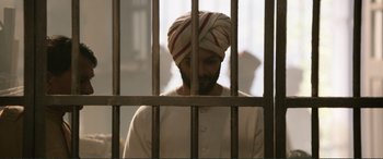 Movie still from “Victoria & Abdul” (2017), directed by Stephen Frears – A man with a turban is behind bars in a jail cell; Medium shot, Low angle
