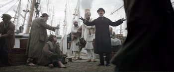 Movie still from “Victoria & Abdul” (2017), directed by Stephen Frears – A group of men standing on top of a dock; Wide shot, Low angle