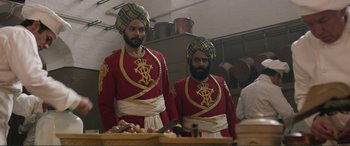 Movie still from “Victoria & Abdul” (2017), directed by Stephen Frears – A couple of men standing next to each other in a kitchen; Medium shot, Low angle