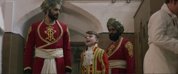 Movie still from “Victoria & Abdul” (2017), directed by Stephen Frears – Three men in red and yellow uniforms and one boy in a red and yellow uniform; Medium shot, Over the shoulder angle
