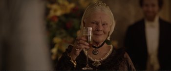 Movie still from “Victoria & Abdul” (2017), directed by Stephen Frears – An older woman holding a glass of champagne; Close Up shot, Low angle