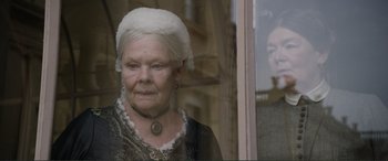 Movie still from “Victoria & Abdul” (2017), directed by Stephen Frears – An older woman wearing a white hat looking out of a window; Close Up shot, Over the shoulder angle