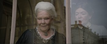 Movie still from “Victoria & Abdul” (2017), directed by Stephen Frears – An older woman wearing a white hat looking out of a window; Close Up shot, Over the shoulder angle