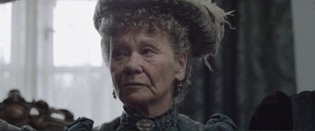 Movie still from “Victoria & Abdul” (2017), directed by Stephen Frears – An older woman with a hat and earrings on; Close Up shot, Over the shoulder angle