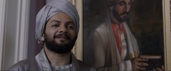 Movie still from “Victoria & Abdul” (2017), directed by Stephen Frears – A man with a turban standing in front of a painting of jesus; Close Up shot, Over the shoulder angle